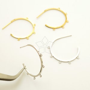 Peut inclure: Trois boucles d'oreilles en forme de cercle avec cinq anneaux de saut sur chaque cercle. Les cercles sont de couleur or et argent.