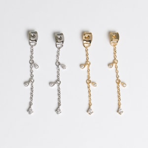 May include: Three pairs of dangle earrings with a delicate chain and small teardrop-shaped crystals. The earrings are available in silver, gold, and rose gold.