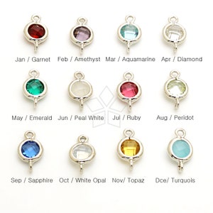 May include: A collection of twelve silver-toned pendants, each featuring a different colored gemstone. The gemstones include garnet, amethyst, aquamarine, diamond, emerald, pearl white, ruby, peridot, sapphire, white opal, topaz, and turquoise.