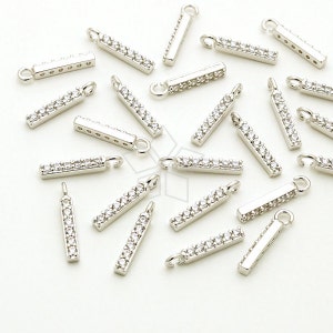 Op de afbeelding: Zilverkleurige rechthoekige sieradenbedels met een rij heldere, sprankelende kristallen. Elke bedel heeft aan één uiteinde een kleine lus om aan sieraden te bevestigen. De bedels zijn verspreid over een wit oppervlak.
