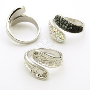 May include: Three silver rings with different designs. One ring is plain, one has clear and black rhinestones, and the other has a textured band.