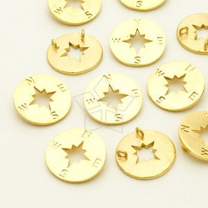 May include: A collection of gold-toned metal compass charms with a star design and the letters N, S, E, and W around the edge.