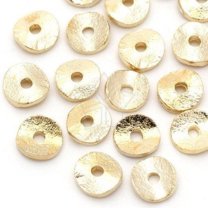 Könnte beinhalten: Eine Sammlung goldfarbener Metall-Spacer-Perlen mit gehämmerter Textur. Die Perlen sind rund mit einem Loch in der Mitte.