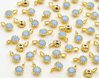 Puede incluir: Una colección de abalorios de metal dorado con piedras de color azul claro que parecen ópalo. Cada abalorio tiene un pequeño bucle para sujetarlo a joyas.
