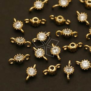 May include: A group of gold-toned metal connector charms with clear crystal accents. Each charm has two loops for attaching to jewellery.