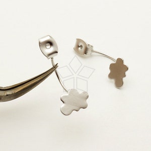 May include: Two silver earring findings with a flower-shaped design. The findings are attached to a silver post with a loop.