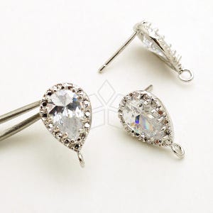 Puede incluir: Dos hallazgos de pendientes de plata en forma de lágrima con piedras de cristal transparentes y un bucle de plata en la parte inferior.