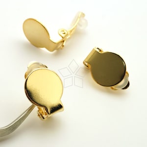 May include: Three gold-tone clip-on earrings with round, smooth fronts. The earrings are designed to be worn without pierced ears.