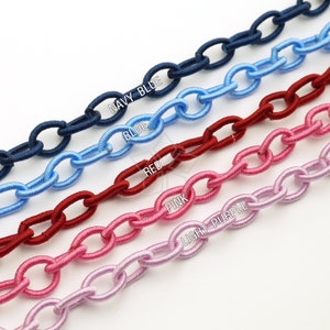 Könnte beinhalten: Nahaufnahme von fünf Ketten in verschiedenen Farben: Marineblau, Hellblau, Rot, Rosa und Hellviolett. Jedes Kettenglied ist oval geformt. Die Farben sind mit dem entsprechenden Namen beschriftet.