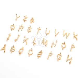 May include: Gold-toned metal alphabet letter charms. Each charm features a different letter of the alphabet. The charms are arranged in alphabetical order.