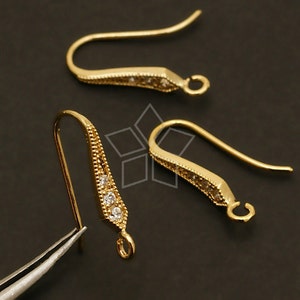Puede incluir: Ganchos para pendientes de tono dorado con detalles de cristal transparente. Los ganchos están diseñados con una ligera curva y un pequeño bucle en el extremo.