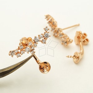 May include: A pair of gold-tone earrings with a curved design and a cluster of clear cubic zirconia stones. The earrings have a post and a butterfly back.