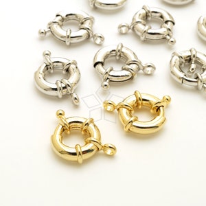May include: A collection of silver and gold metal ring clasps for jewelry making. The clasps are round and have a decorative design.