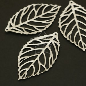 May include: Three silver metal leaf-shaped cutouts with intricate designs. The leaves are delicate and have a filigree pattern.