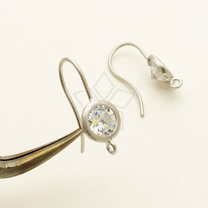 May include: A pair of silver earring hooks with clear round crystal stones.
