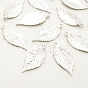 May include: Silver leaf charms with intricate veining and a small loop for attaching to jewellery. These charms are suitable for necklaces, earrings, or bracelets. The leaves have a textured surface and a realistic appearance.