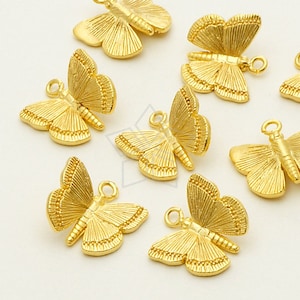 May include: A selection of gold-coloured butterfly charms. Each charm has detailed wing patterns and a small loop for attaching to jewellery or other crafts. The butterflies are arranged on a white surface.