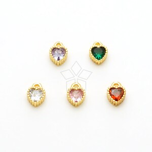 May include: Five gold heart-shaped charms with different colored crystal centers. The charms are on a white background. The colors of the crystals are clear, pink, green, and red.