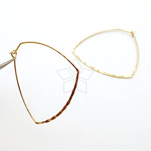 May include: A pair of gold-toned hoop earrings with a geometric, teardrop shape. The earrings have a hammered texture.