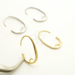 May include: Three pairs of hoop earrings in silver and gold. The earrings are oval shaped and have a textured finish.