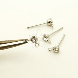 May include: Four silver earring posts with clear rhinestone accents. Each post has a small loop at the end.