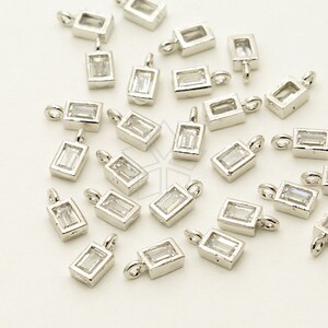 May include: A group of silver-toned pendant charms with clear rectangular stones. Each charm has a loop for attaching to a necklace or bracelet.