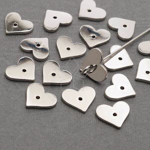 May include: A collection of silver metal heart-shaped charms with a hole in the center. The charms are scattered on a gray surface.