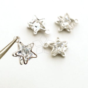 Puede incluir: Cuatro abalorios de estrella plateados con detalles de cristal transparente. Cada abalorio tiene un bucle para sujetarlo a joyas u otras manualidades.