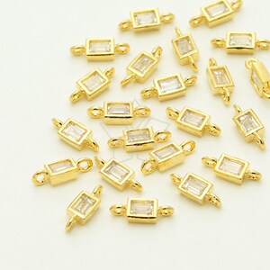 May include: A group of 20 gold-toned connector charms with clear rectangular stones. Each charm has two loops for attaching to jewelry.