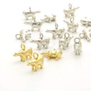 May include: A collection of silver and gold polar bear charms. The charms are in various poses, including standing, sitting, and lying down. The charms are perfect for adding a touch of whimsy to jewelry or crafts.