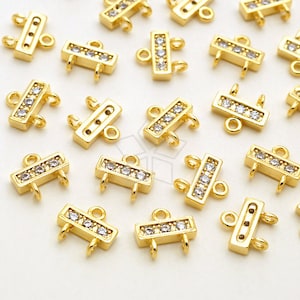 May include: Gold-toned jewelry connectors with clear, sparkling crystals. These rectangular connectors have multiple loops for attaching to other jewelry components. The connectors are designed for jewelry making and crafting.