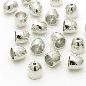 May include: A collection of silver-toned metal end caps for jewellery making. The end caps are oval-shaped with a smooth, shiny finish. Some end caps have a domed top, while others have a flat top.