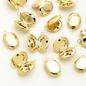 May include: A collection of gold-colored oval lockets, some open and some closed. The lockets have a shiny, reflective surface and a small loop at the top for attaching a chain. The open lockets reveal a small interior space.