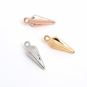 May include: Three metal pendant charms in rose gold, silver, and gold. Each charm is a stylized, pointed shape with a small loop at the top for attaching to jewellery. The charms are displayed against a white background.