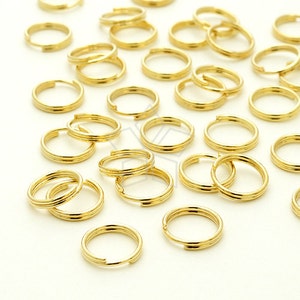 Puede incluir: Una gran cantidad de anillos de salto de color dorado. Los anillos son todos del mismo tamaño y están dispuestos en un patrón aleatorio.