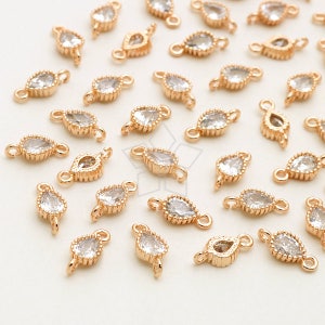 May include: A group of gold-toned metal connectors with clear crystal accents. Each connector has two loops for attaching jewellery pieces.