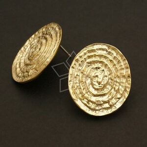 May include: A pair of gold-toned earrings with a circular design. The earrings have a textured, concentric circle pattern.