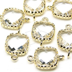 May include: A group of seven gold-toned crystal charms with a square shape and a faceted design. Each charm has a loop on the top and a bail on the bottom.