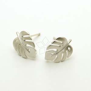 May include: A pair of silver earrings shaped like monstera leaves.