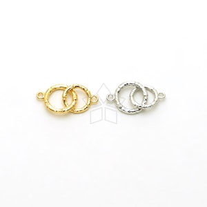 May include: Two interlocking gold and silver rings with textured surfaces. Each ring has a small loop on the side for attaching to jewellery.