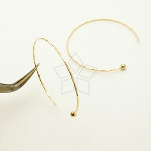 May include: Two gold hoop earrings with a hammered texture and a small ball at the end of each hoop.