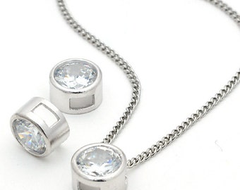 May include: A silver chain necklace with two round clear crystal pendants. The pendants are set in a silver bezel.