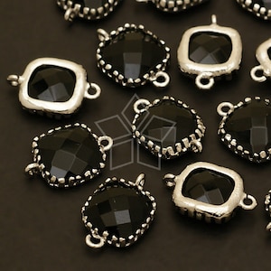 May include: Black faceted glass square charms with silver-toned metal frames and jump rings. The charms have a decorative edge.
