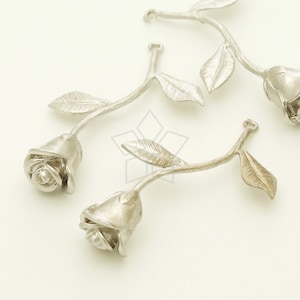 May include: Three silver rose charms with a stem and leaves. The roses are detailed and have a realistic look.