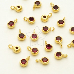 May include: A collection of 18 gold-tone pendant charms with a small red rhinestone in the centre. Each charm has a loop at the top for attaching to a necklace or bracelet.