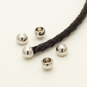 May include: Five silver metal beads with a hole in the center, and a brown leather cord. The beads are round and shiny.