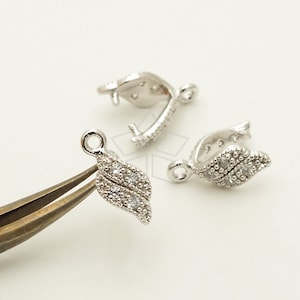 May include: Three silver-toned leaf-shaped clasps with clear crystal accents. Each clasp has a loop at the top for attaching to a necklace or bracelet.