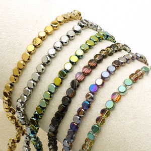 May include: A set of seven strands of iridescent glass beads. The beads are faceted and have a variety of colours, including gold, silver, green, blue, and purple.