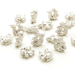 May include: A collection of silver squirrel charms, some holding nuts, others with their tails curled. These charms are perfect for adding a touch of whimsy to jewelry or crafts.