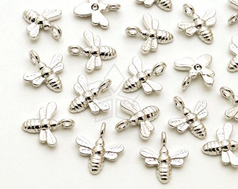 Puede incluir: Una colección de abalorios de abeja plateados con un bucle para sujetar a joyas u otras manualidades.